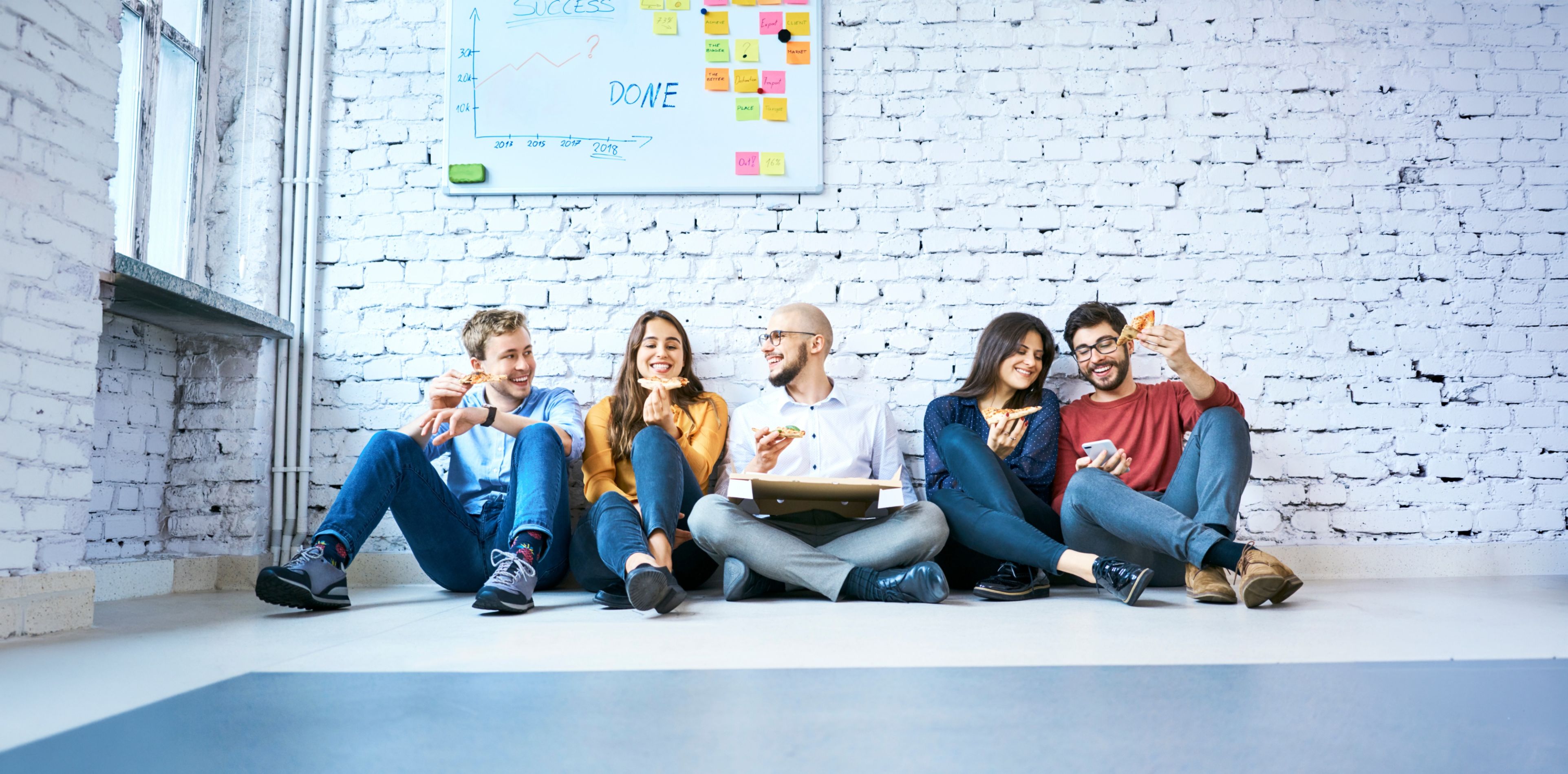 Gruppe an Personen sitzend vor Steinwand